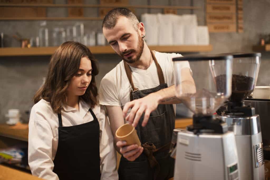 man-showing-woman-cup-with-coffee-machine