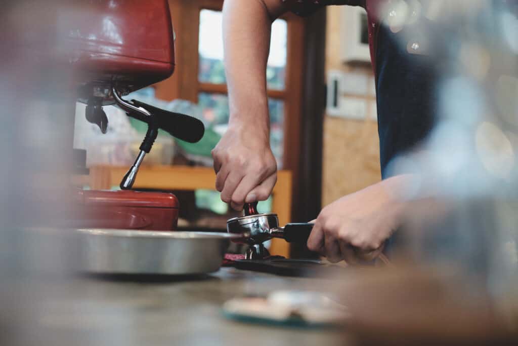 Barista tamping freshly ground coffee in a portafilter